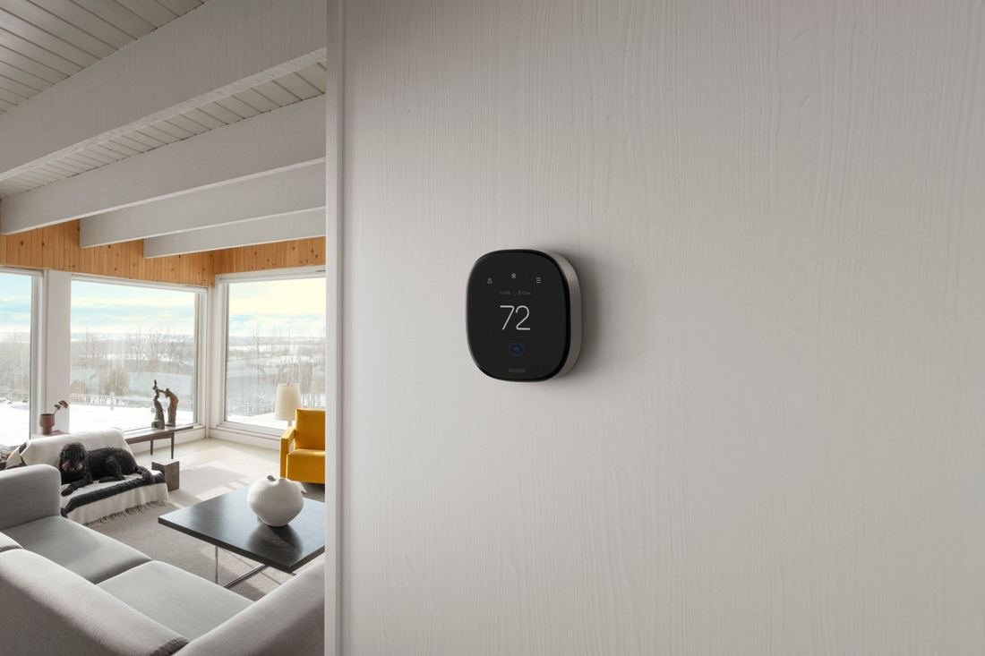 ecobee Smart Thermostat Premium mounted on a white wall next to a bright living room