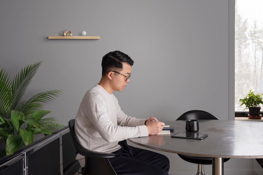 ecobee SmartSensor on a wall shelf in a home office while a man works at a table