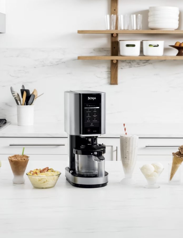 Ninja CREAMi on a kitchen counter surrounded by ice cream, a milkshake, a smoothie bowl, and a cone
